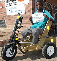 African man with both legs amputed in his new PET wooden hand crank cart