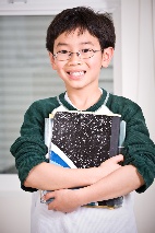 Boy smiling holding school notebooks. 