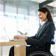 business woman in wheelchair working on laptop at a desk