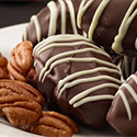 Date pecan chocolate truffles on a plate with pecans.