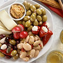 Plate with almonds, olives, stuffed peppers, cheese, and dip.