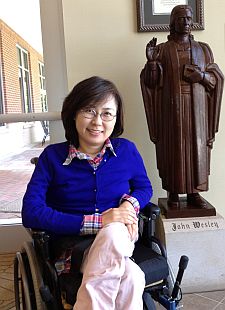 Jinwook Oh seated in wheelchair in front of John Wesley statue