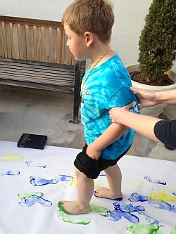 Boy with painted feet walking on butcher paper