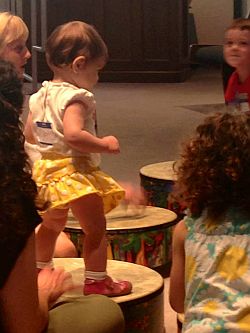 Child walking on drums as others watch