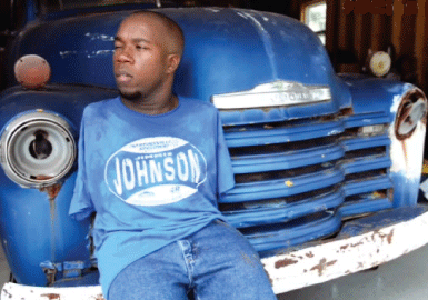 Richie Parker sitting on his blue restored vehicle