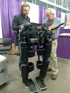 Two men examining the Ekso exoskeleton. 
