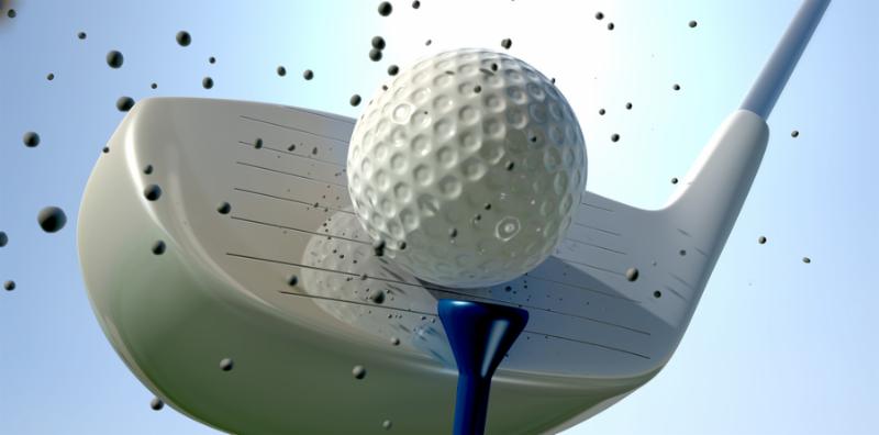 An extreme close up of a golf ball being hit off its tee with a club on a blue sky background